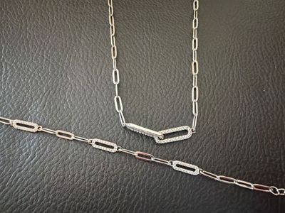 a close up of a silver chain on a black leather surface