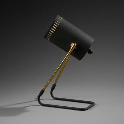 une lampe noire posée sur un pied en métal, avec un abat-jour noir