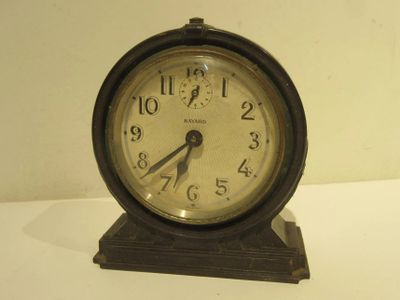 a small clock sitting on top of a white table