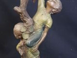 bronze statue of a boy climbing a tree with a bird on his shoulder