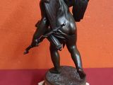 a statue of a boy holding a bird on top of a table