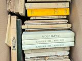 many books stacked in a box on the floor