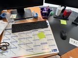 a desk with a computer, keyboard, mouse and other office supplies on it