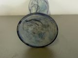 a glass vase sitting on a table with a white wall in the background
