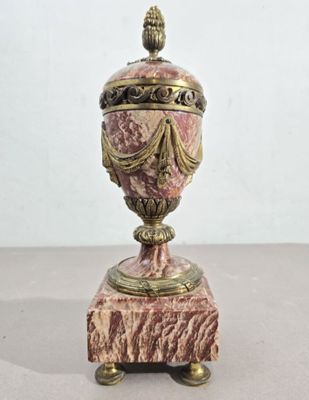 urne antique en marbre rose rehaussée de touches dorées, posée sur un socle en marbre