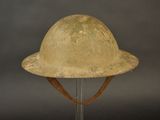 an old helmet on a metal stand against a gray background