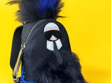 the small black bag has a furry animal on it ' s side