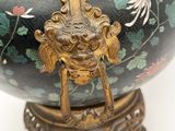 a black vase with a gold handle on a stand