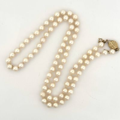 a close up of a white pearl necklace with a gold clasp