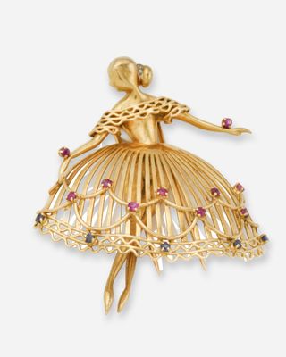 un gros plan sur une broche en or représentant une ballerine