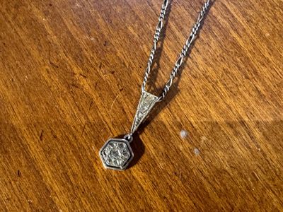 un collier en argent posé sur une table en bois, orné d'un pendentif en argent