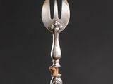 a silver spoon with a fork sticking out of it sitting on a table