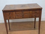 a small wooden table with three drawers on it