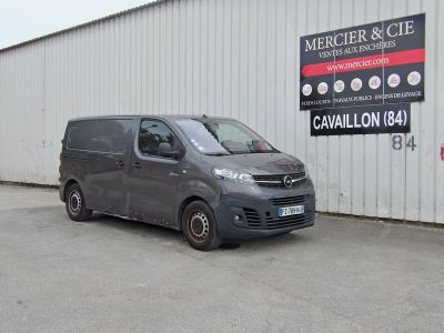 une camionnette garée devant un immeuble sur lequel est accrochée une pancarte