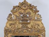 a mirror that has a gold frame with a picture on it
