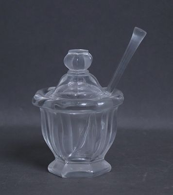 un bocal en verre contenant une cuillère, posé sur une table