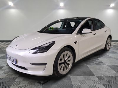 the white tesla model 3 is parked on a checkered floor