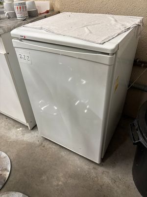 a white refrigerator sitting next to a black trash can