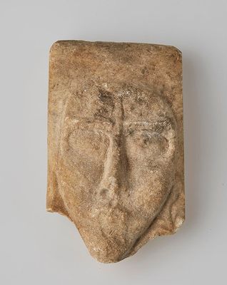 une tête d'homme sculptée dans la pierre, avec une croix sur le front