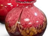 two red vases sitting next to each other on a white surface