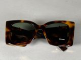 des lunettes de soleil à monture écaille posées sur une table blanche, sur fond blanc