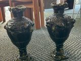 two black vases sitting on the floor in a room
