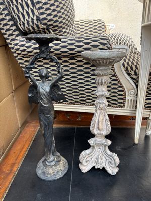 une statue représentant un garçon tenant un bac à oiseaux posé sur une table à côté d'une chaise