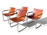 trois fauteuils en cuir marron placés les uns à côté des autres sur une surface blanche