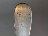 a silver spoon with writing on it sitting on a table