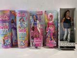 Plusieurs poupées Barbie sont alignées sur une étagère