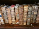 de nombreux livres anciens posés sur une étagère dans une pièce