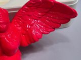 a red angel figurine sitting on top of a white box
