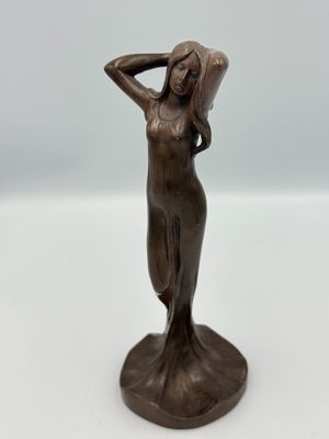 une statue en bronze représentant une femme, les mains posées sur la tête