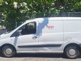 a white van parked in a parking lot with trees in the background