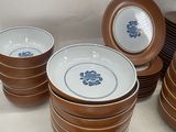 several brown and white plates and bowls with blue flowers on them