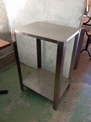 a metal table with a shelf on it in a room
