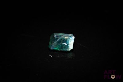 an emerald stone on a black surface in the dark