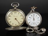 deux montres de poche en argent posées l'une à côté de l'autre sur une surface noire