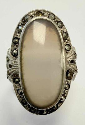 une bague ovale sertie d'une pierre blanche entourée de diamants noirs