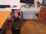 a desk with a computer, speakers, and a monitor on it