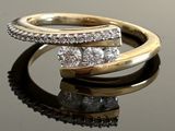 a close up of a gold and diamond ring on a reflective surface