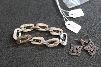 deux bijoux posés sur une table, à côté d'un sachet de thé