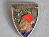 un gros plan sur un insigne métallique représentant un homme coiffé d'un chapeau rouge
