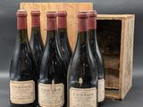 quatre bouteilles de vin rouge dans un coffret en bois posé sur une table