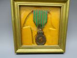 gold framed picture of a medal with a green ribbon in a gold frame