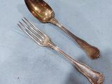 two silver spoons and a fork on a table