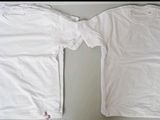 two white t - shirts sitting next to each other on a table