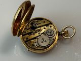 a small gold pocket watch with gears inside of it