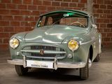 a green car that is parked in front of a brick wall
