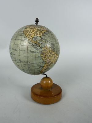 a small globe on a wooden stand with a white background